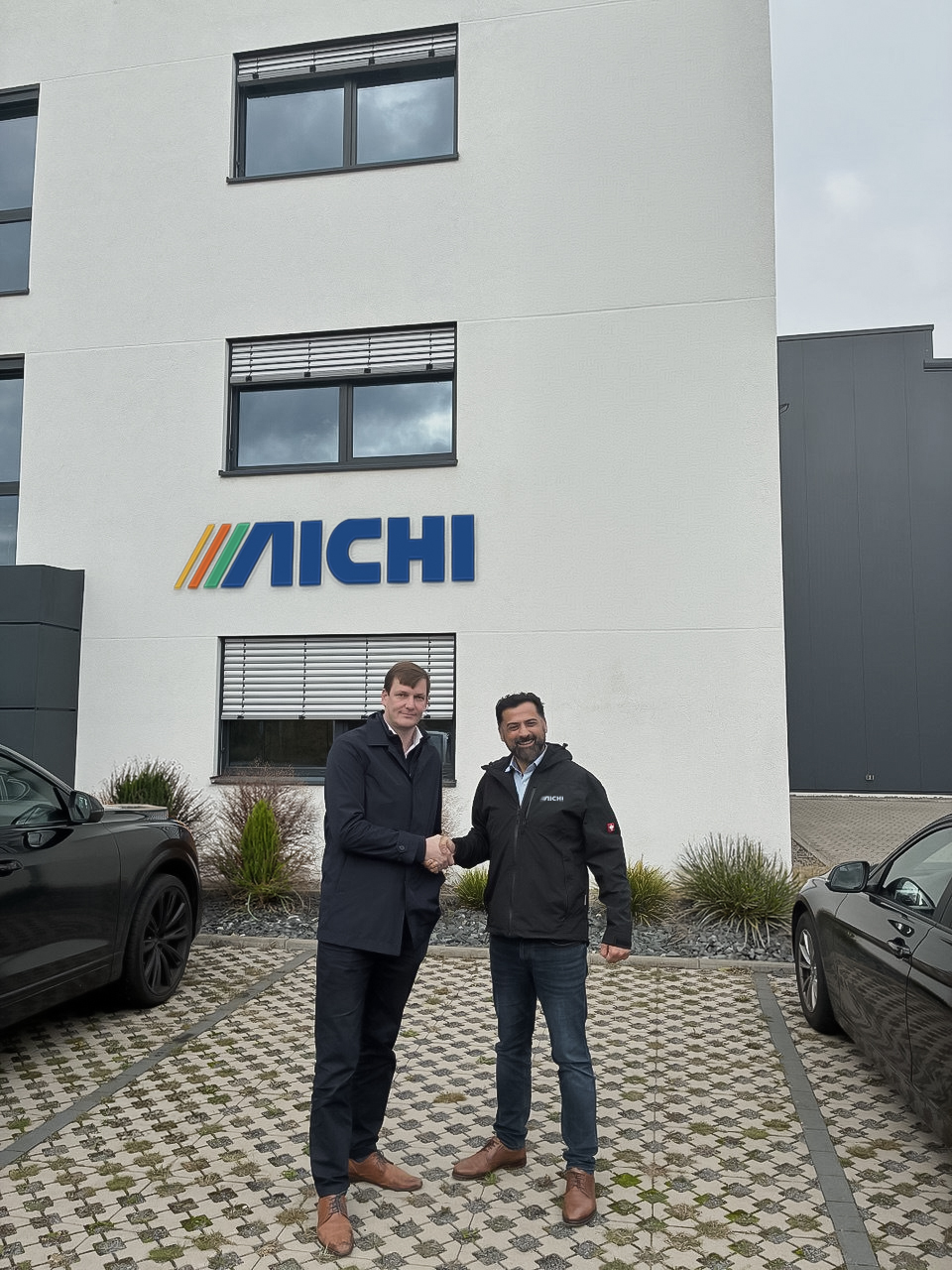 Vertimac und Aichi Sales Office BV besiegeln ihre Partnerschaft für Belgien und Luxemburg vor dem AICHI-Gebäude.